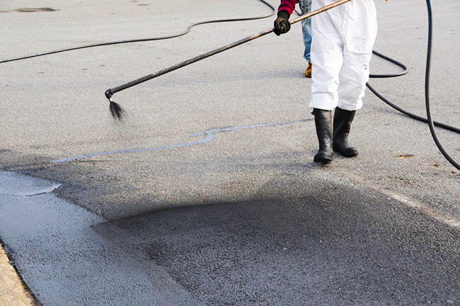 worker spraying tar sealant