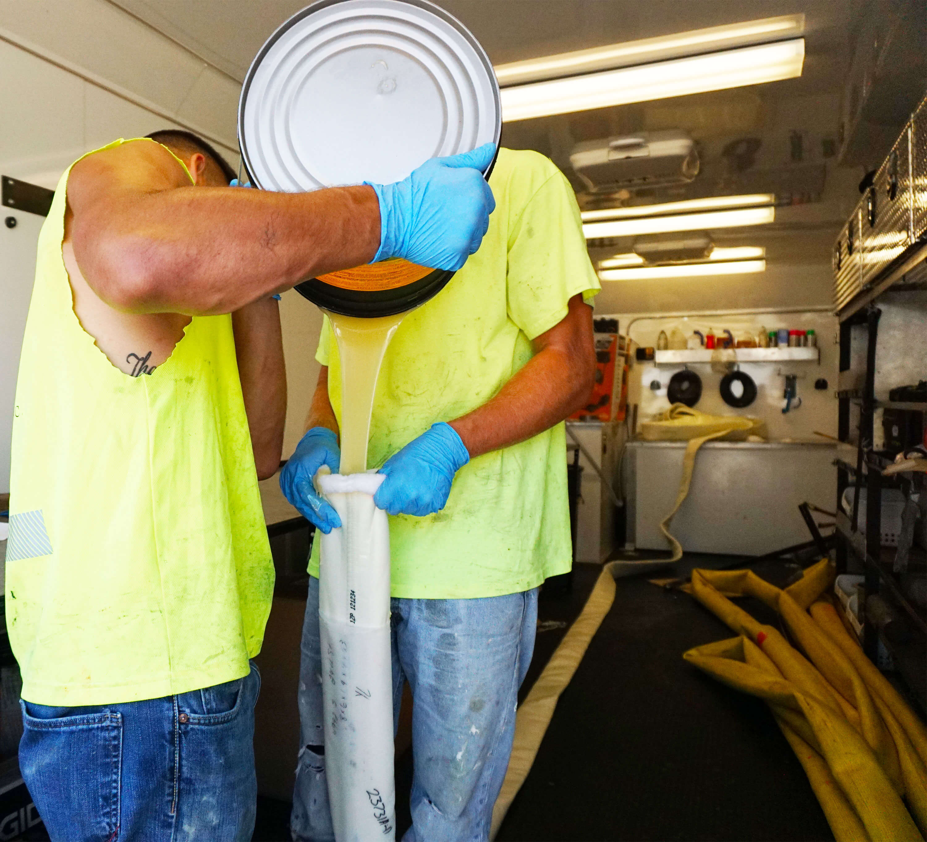 two men pouring liquid polymer into a bag