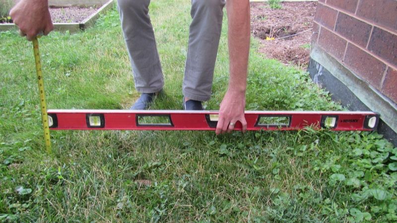 man measuring grading around his home