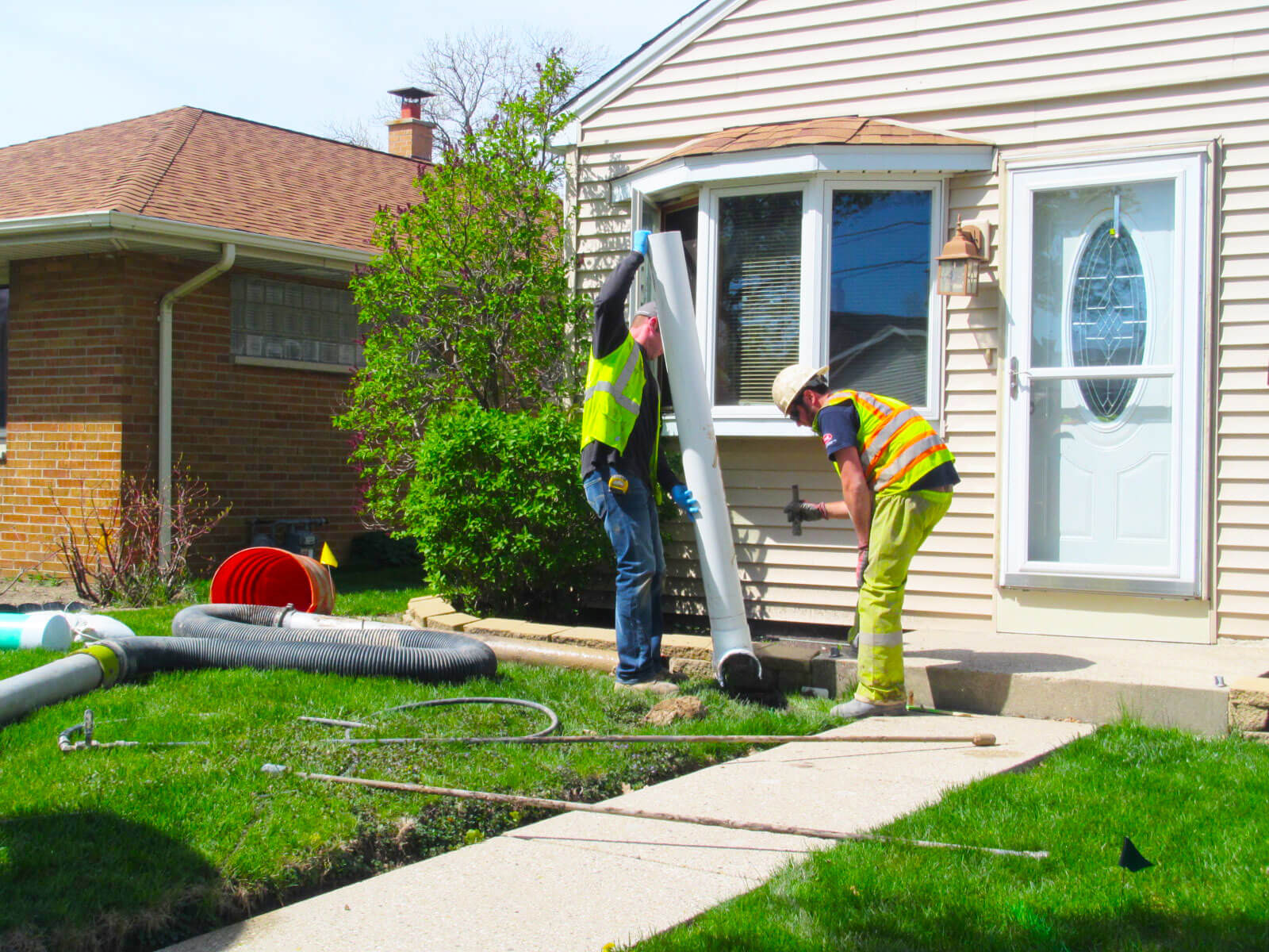 two workers inspecting a home's lateral sewer pipe